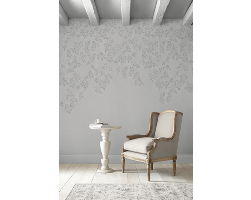 Einrichtungsszene mit Sessel, Beistelltisch und Tapete mit Blattmuster in einem hellen Raum.