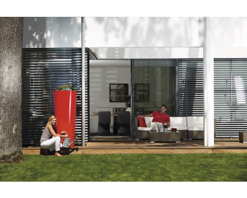 Szene mit einem hohen Regenwassertank, einer Frau mit einer Gießkanne und einem Mann auf einer Terrassencouch