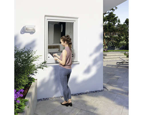 Frau bedient Fenster mit Tablet im Außenbereich