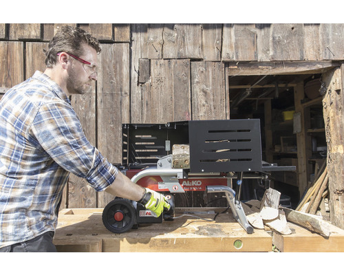 Ein Mann bedient einen Holzspalter von AL-KO vor einer Holzwand.