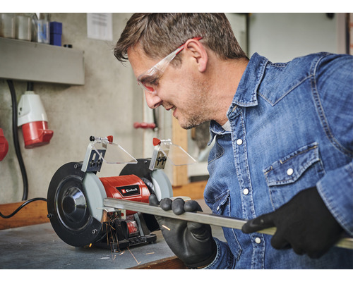 Mann schleift Metallstange mit einer Doppelschleifmaschine von Einhell