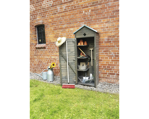 Gartenschrank aus Holz mit offenstehender Tür und Gartenzubehör vor einer Backsteinmauer