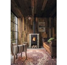 Wohnzimmer mit Holzvertäfelung, Ofen, Sessel und Sofa.