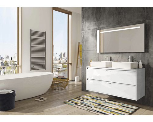 Helles Badezimmer mit Badewanne, Handtuchwärmer, Waschtisch mit zwei Waschbecken und beleuchtetem Spiegel.