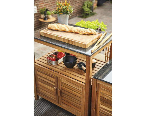 Grillwagen mit Schneidebrett, Zubehör und Lebensmitteln im Außenbereich.