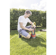 Ein Mann hockt auf einem Rasen und schliesst einen gelben Schlauch an eine Tauchpumpe von Al-Ko an.