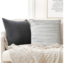 Zwei dekorative Kissen mit einem Stricküberwurf auf einem Sofa.