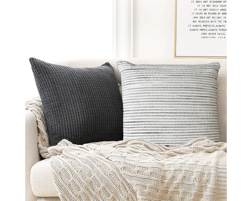 Zwei dekorative Kissen mit einem Stricküberwurf auf einem Sofa.