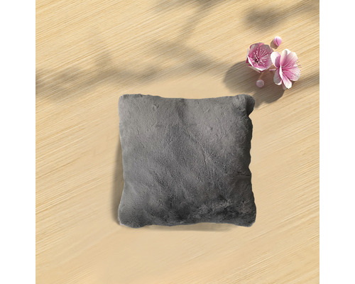 Graues Kissen auf einem Holztisch mit Blüten