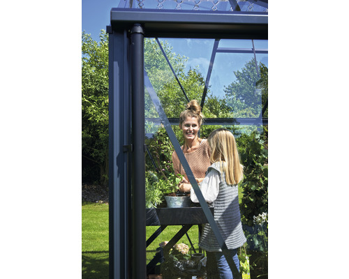 Frau und Kind arbeiten in einem Gewächshaus.