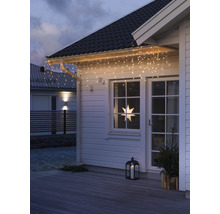 Hausfassade mit Lichterkette, Fensterstern, Laterne und kleinem Tannenbaum für eine festliche Dekoration