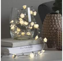 Dekorative Lichterkette mit Rosen und Blättern in einem Glas