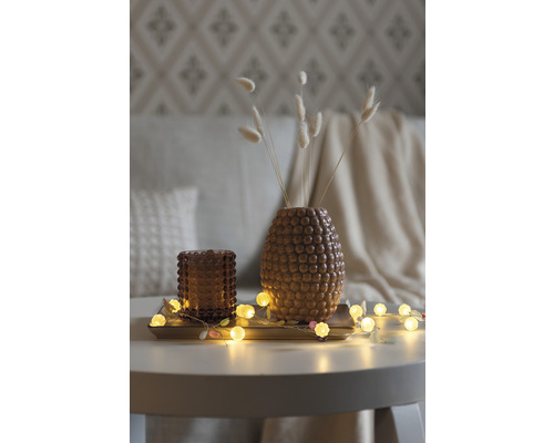 Dekoration mit Vase, Teelichthalter und Lichterkette auf einem Tisch