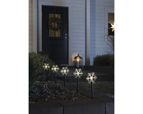 Dekorative Schneeflockenleuchten im Vorgarten eines Hauses mit Kranz an der Tür