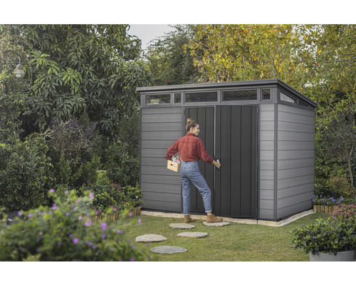 Garten Szene mit Gerätehaus und Frau, die eine Kiste trägt