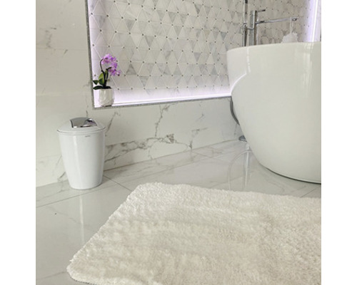 Badezimmer mit freistehender Badewanne, Toilette, flauschigem Teppich und dekorativer Wandgestaltung