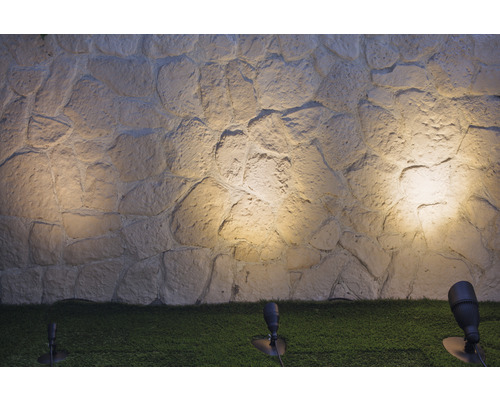 Steinwand beleuchtet mit Gartenspots auf Rasenfläche