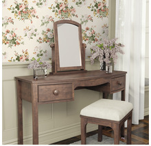 Schminktisch mit Spiegel und Hocker vor einer floralen Tapete