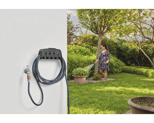 Gartenszene mit Schlauchwagen und Frau beim Bewässern des Gartens