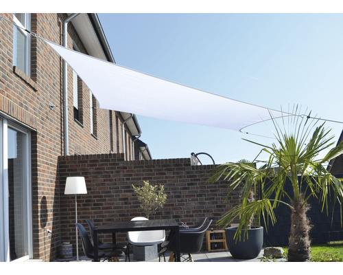 Terrasse mit Sonnensegel, Tisch und Stühlen vor einem Backsteingebäude