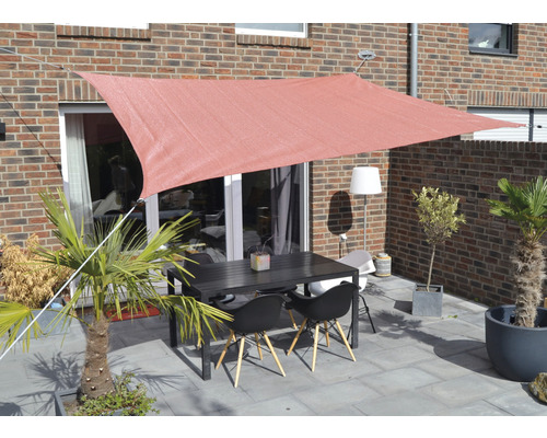 Terrasse mit Sonnensegel, Tisch und Stühlen vor einem Backsteingebäude