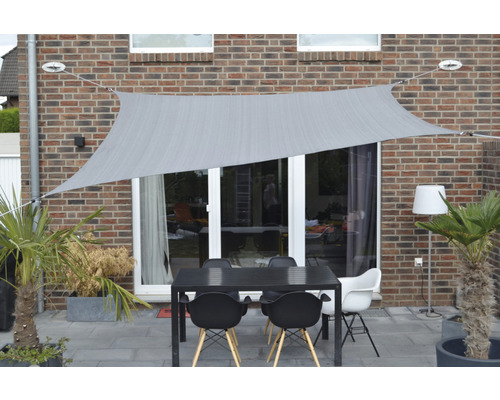 Terrasse mit Sonnensegel, Tisch und Stühlen vor einer Hauswand