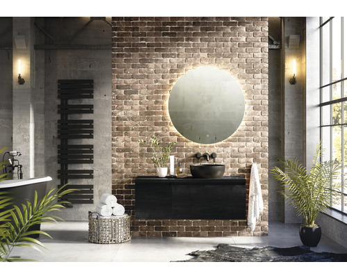 Modernes Badezimmer mit freistehender Badewanne, Handtuchwärmer, Waschtischunterschrank, rundem Spiegel mit Beleuchtung und Ziegelwand