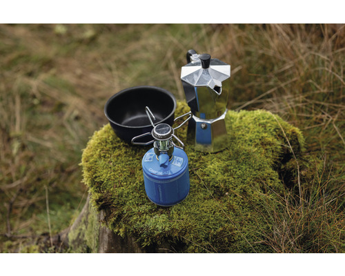 Campingkocher, Kaffeekanne und Schüssel auf einem Baumstumpf