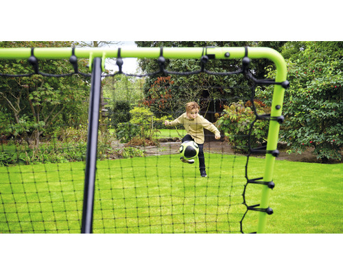 Junge spielt mit einem Ball vor einem Fußballtor im Garten.