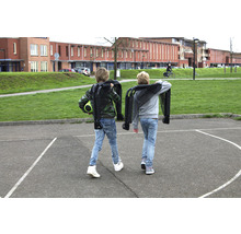 Zwei Kinder tragen zusammengeklappte Bollerwagen auf einem Schulhof.