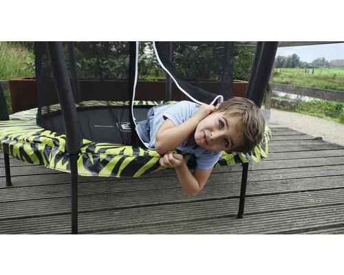 Kind liegt auf Gartentrampolin mit Sicherheitsnetz