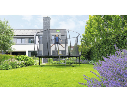 Trampolin mit Sicherheitsnetz und springendem Kind im Garten