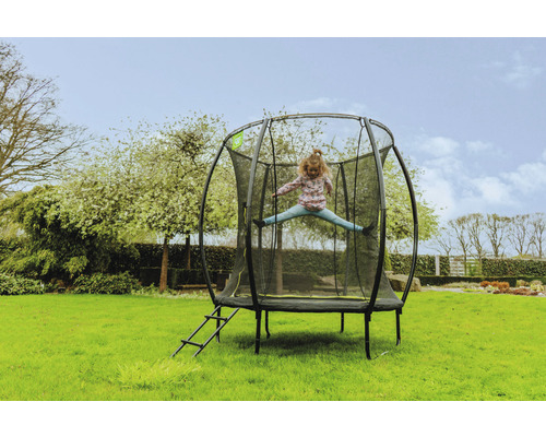 Mädchen springt auf einem Gartentrampolin mit Sicherheitsnetz und Leiter