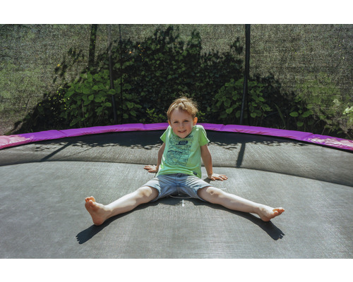 Ein Junge sitzt auf einem Gartentrampolin.