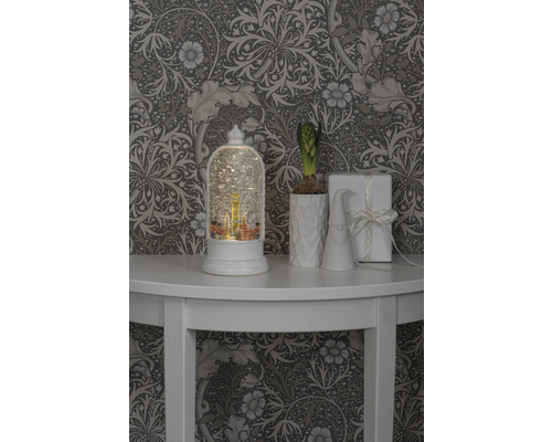 Dekorative Szene mit Schneekugel, Pflanze, Wichtel und Geschenk auf einem Tisch