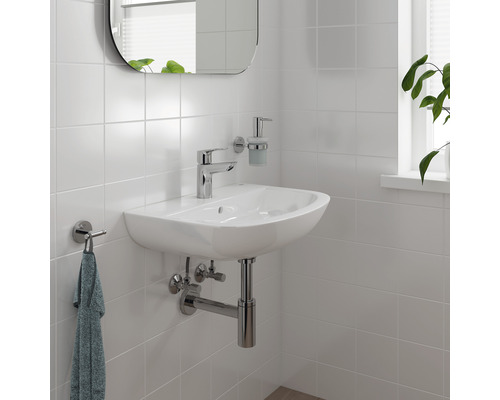 Helles Badezimmer mit weißem Waschbecken, Armatur, Spiegel und Handtuchhalter an der Wand.