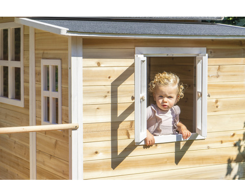 Kind schaut aus dem Fenster eines Holzspielhauses