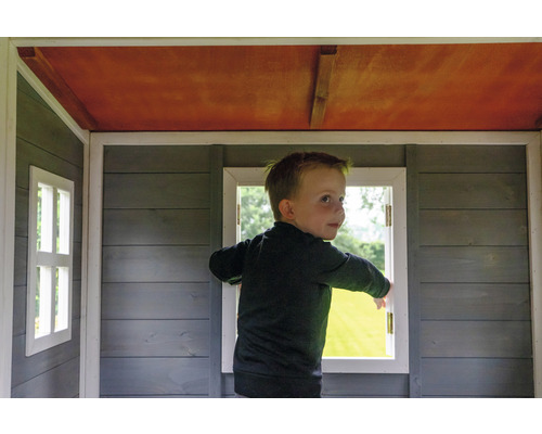 Kind im Spielhaus mit Holzfenstern und Holzwänden