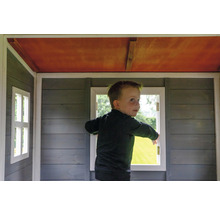 Ein Kind steht in einem Holzspielhaus mit Fenstern