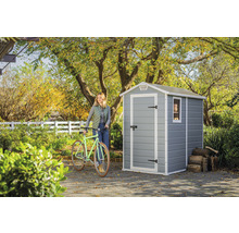 Gartenszene mit Gerätehaus, Fahrrad und Frau im Garten