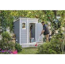 Gartenszene mit Gerätehaus und Mann beim Laub rechen