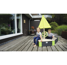 Sandkasten in Bootsform mit Segel und zwei spielenden Kindern im Garten.