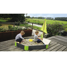 Sandkasten in Bootsform mit zwei spielenden Kindern im Garten.