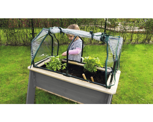 Hochbeet mit Frühbeetaufsatz und Kind beim Gärtnern im Garten.