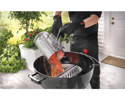 Person gießt glühende Grillkohle mit einem Anzündkamin in einen Holzkohlegrill