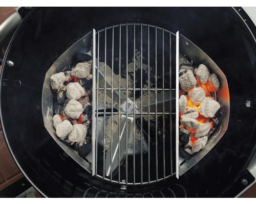 Grill mit Kohlenkörben und glühenden Grillbriketts unter einem Grillrost