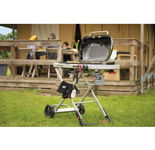 Weber Traveler Gasgrill mit Grillwerkzeugen und Gasflasche vor dem Zelt