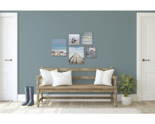 Wohnraum mit dekorativen Wandbildern mit Strandmotiven über einer Holzbank