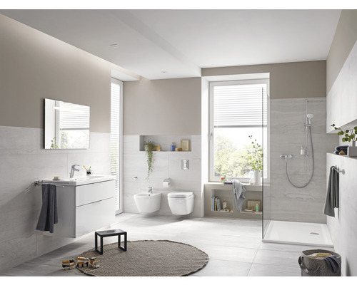 Helles Badezimmer mit Waschtisch, Spiegel, Bidet, Toilette und Dusche.