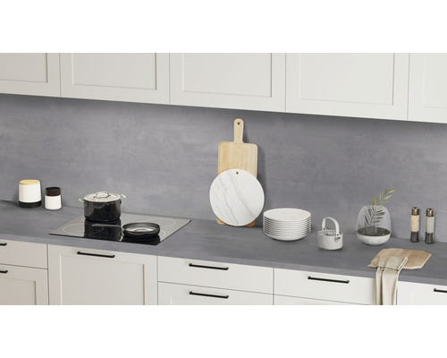 Küchenszene mit Arbeitsplatte, Kochfeld, Kochutensilien und Geschirr vor weißen Schränken